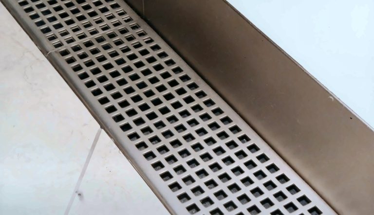 Square hole perforated metal grille set into a floor