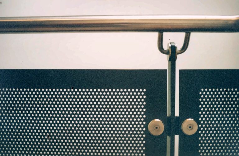 Perforated metal balustrade panel with handrail fixing