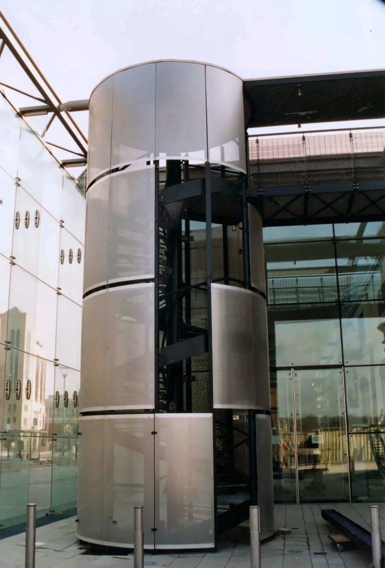 Stair tower clad in curved perforated metal sheet